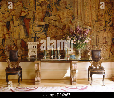 Chaises en cuir et doré de chaque côté d'une table en verre avec en jambes et grand affichage floral devant de grandes tapes Banque D'Images