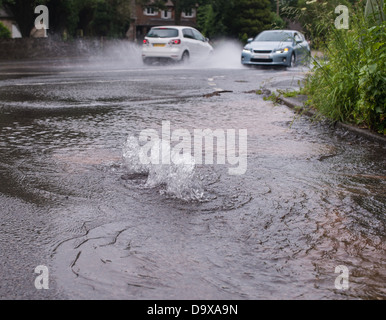 Les voitures qui circulent dans la route inondée d'eau causés par burst Banque D'Images