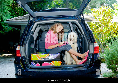 Teen girl with shopping bags and dog in car Banque D'Images