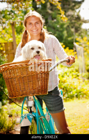 Teen girl sur vélo avec panier à chien Banque D'Images