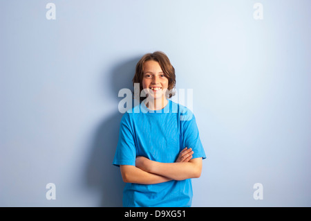 Smiling teenage boy leaning on wall - bras croisés Banque D'Images