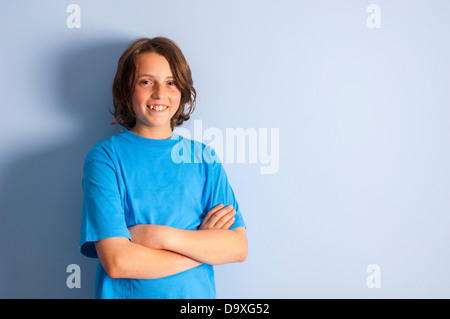 Smiling teenage boy leaning on wall - bras croisés Banque D'Images