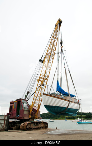 Image Portrait montrant un vieux yacht de l'arrachage par grue de la cale de halage d'une rivière. Banque D'Images