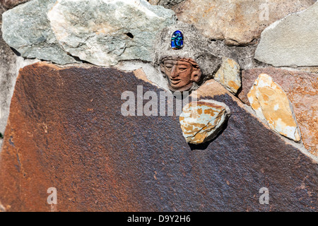 Petit indien de la tête sculptée en pierre bleue intégré dans un mur de pierre qui entoure le jardin d'enfants à Kanapaha Jardins. Banque D'Images