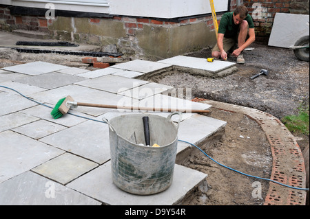 Construction d'un patio pose pavage en pierre naturelle, l'homme le réglage du lit de mortier Banque D'Images