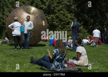 Des gens assis sur l'herbe dans un parc. Banque D'Images