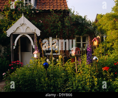 Maisons d'oiseaux en bois sur bois parmi la floraison des plantes d'été dans le jardin de chalet avec porche blanc Banque D'Images