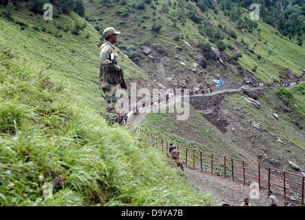 Baltal, Cachemire indien 28 juin 2013. Un policier indien monte la garde comme dévots hindous à pied durant leur pèlerinage de Baltal Camp de base à la Sainte Grotte Amarnath Shrine, à Baltal . Chaque année, des centaines de milliers de pèlerins à travers les montagnes perfides en révolte-déchiré le Cachemire, le long de rivières glacées, des glaciers et des lacs gelés, des laissez-passer pour atteindre l'Amarnath grotte, située à une altitude de 3 857 mètres (12 729 pieds), où un Shiva Lingam, une stalagmite de glace en forme de phallus et symbolisant le dieu hindou Shiva, est synonyme de culte. (Sofi Suhail/ Alamy Live News) Banque D'Images