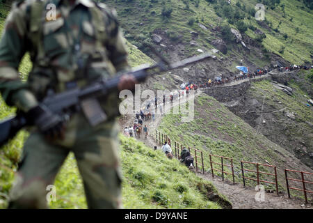 Baltal, Cachemire indien 28 Juin 2013.Un policier indien monte la garde comme dévots hindous à pied durant leur pèlerinage de Baltal Camp de base à la Sainte Grotte Amarnath Shrine, à Baltal . Chaque année, des centaines de milliers de pèlerins à travers les montagnes perfides en révolte-déchiré le Cachemire, le long de rivières glacées, des glaciers et des lacs gelés, des laissez-passer pour atteindre l'Amarnath grotte, située à une altitude de 3 857 mètres (12 729 pieds), où un Shiva Lingam, une stalagmite de glace en forme de phallus et symbolisant le dieu hindou Shiva, est synonyme de culte. (Sofi Suhail/ Alamy Live News) Banque D'Images