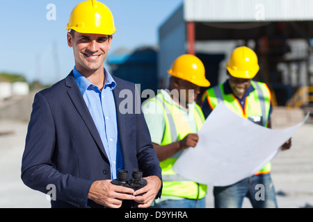 Smiling Caucasian surveillant de la construction avec des jumelles Banque D'Images
