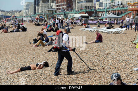 Brighton UK 29 juin 2013 - Un chasseur de trésor avec un dispositif de détection de métal marche au milieu des baigneurs sur la plage de Brighton comme ils ont apprécié le temps chaud aujourd'hui photographie prise par Simon Dack/Alamy Live News Banque D'Images