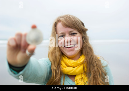 Image de jeune femme tenant un dollar de sable sur la plage de Manzanita, Oregon. Banque D'Images