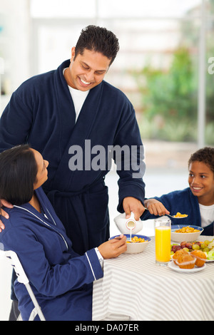 Verser le lait pour mari aimant femme sur table du petit déjeuner Banque D'Images