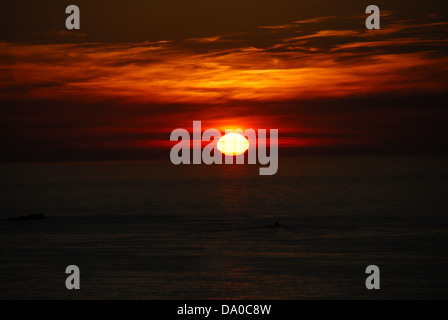 Le soleil se couche alors que le ciel s'allume en orange foncé. Banque D'Images