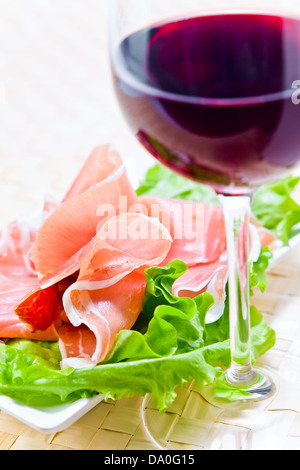 Verre à vin rouge et le jambon avec salade Banque D'Images