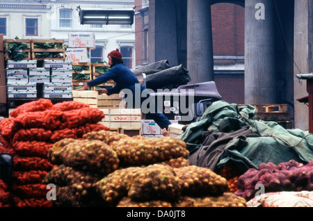 Photographie vintage d'un chauffeur de camion ou d'un travailleur du marché déchargeant des boîtes de légumes et des sacs de légumes oignons carottes à l'extérieur de l'église St Paul à l'ancien marché de légumes Covent Garden à Londres Angleterre Royaume-Uni 1970s 1972 KATHY DEWITT Banque D'Images