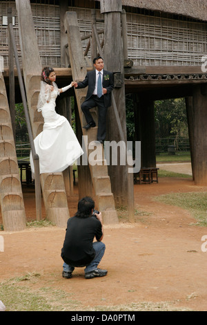 Couple pose pour photo de mariage en face de la maison de village traditionnelle, Musée vietnamien d'Ethnologie, Hanoi, Vietnam Banque D'Images