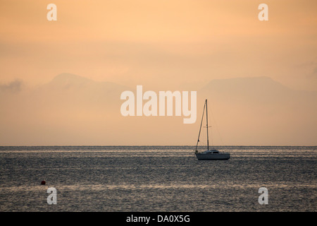 Bateau solitaire dans la baie de Tremadog avec Rhinog au lever du soleil derrière les montagnes brumeuses Snowdonia Gwynedd au nord du Pays de Galles UK Banque D'Images