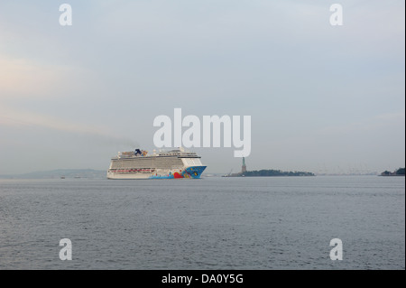 Norwegian Cruise Line's Norwegian Breakaway dans le port de New York, en passant devant la Statue de la liberté à l'aube. Banque D'Images