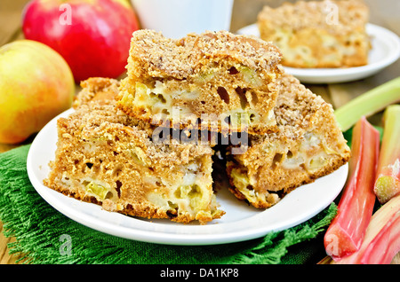 Des morceaux de gâteau sucré à la rhubarbe et les pommes sur une serviette verte, cup sur l'arrière-plan de planches en bois Banque D'Images