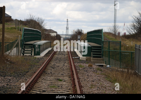 Passage à niveau ligne de chemin de fer désaffectée sur une vieille route pont. Les voies de chemin de fer rouillé, un chariot d'achat abandonné et négligence générale. Banque D'Images