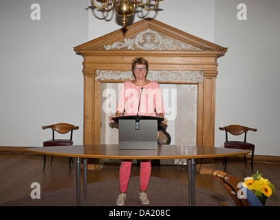 Femme debout derrière le bureau et parlant à travers le microphone Banque D'Images