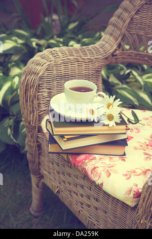 Tasse de thé avec un livre et de camomille sur une chaise Banque D'Images