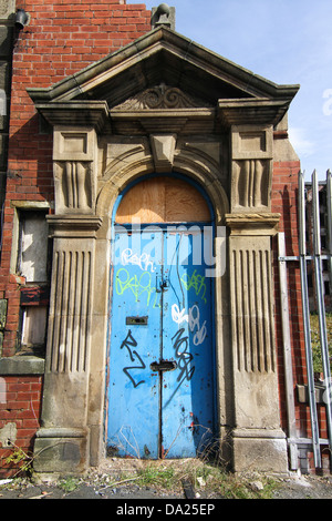 Une porte bleue sur un bâtiment abandonné de graffiti et des barrières de sécurité. Évidemment rien derrière. Banque D'Images