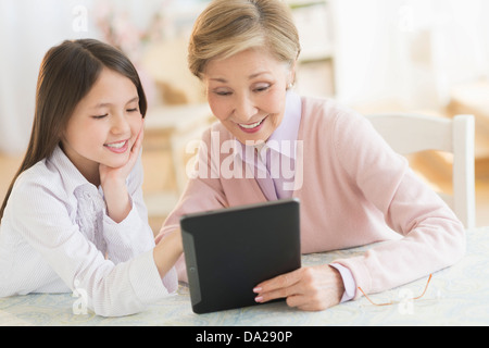 Petite-fille (8-9) et grand-mère using digital tablet Banque D'Images