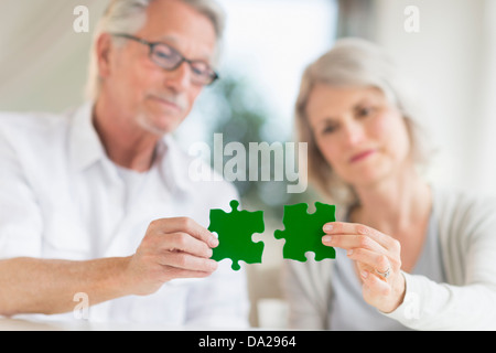 Senior couple holding pièces de puzzle correspondant Banque D'Images