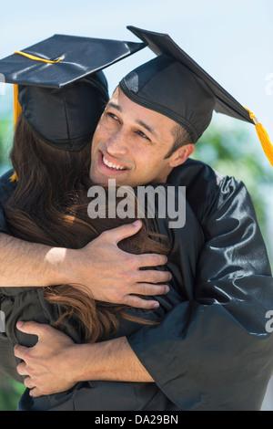 Les étudiants masculins et féminins embrassant sur la cérémonie de remise de diplômes Banque D'Images