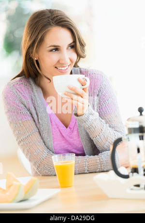 Jeune femme à boire le thé à table Banque D'Images