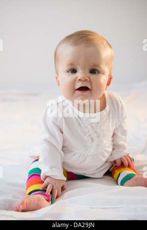 Portrait of baby girl (6-11 mois) sitting in bed Banque D'Images