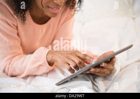 Portrait of woman using digital tablet in bed Banque D'Images