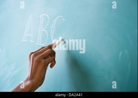 Close up of woman's hand writing on blackboard alphabet Banque D'Images