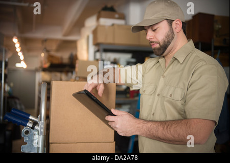 Delivery man holding dans l'entrepôt d'informations portable device Banque D'Images