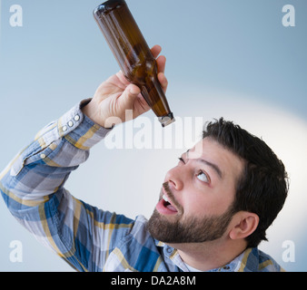 Portrait d'homme tenant une bouteille de bière vide et à l'Analyser Banque D'Images