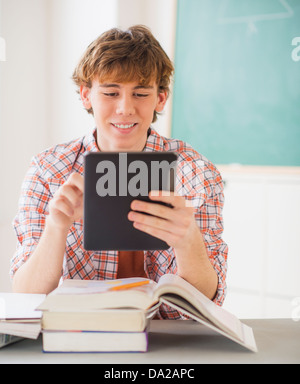 Teenage boy (14-15) sitting in classroom with tablet pc Banque D'Images