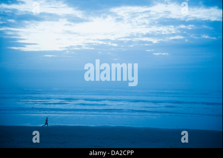 USA, Ohio, Rockaway Beach, vue éloignée sur woman running along beach Banque D'Images