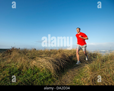 USA, Ohio, Rockaway Beach, jeune adulte homme court sur dune Banque D'Images