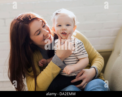 Portrait de Mère assis sur un canapé et toucher de sa fille visage (12-17 mois) Banque D'Images