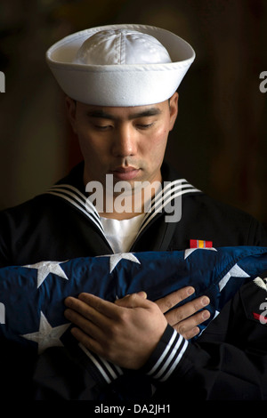 Un marin de l'US Navy porte le drapeau lors d'une inhumation en mer à bord de San Antonio-classe de transport amphibie USS dock Anchorage 13 mai 2013, à Anchorage, AK. Banque D'Images