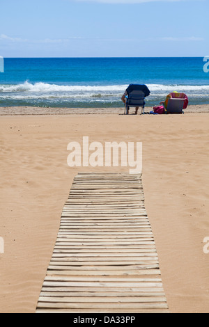 Personnes en chaises de plage à l'extrémité de la plage de lattes de bois fauteuil roulant Rampe d'accès Banque D'Images