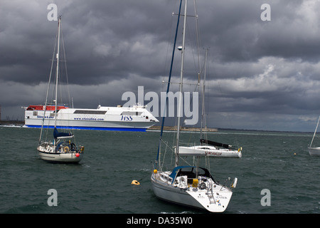 Une vedette rapide HSS de Stena Line passe devant des yachts à voile amarrés dans le port de Dún Laoghaire, en Irlande, sous des nuages d'orage en mai 2013. Banque D'Images