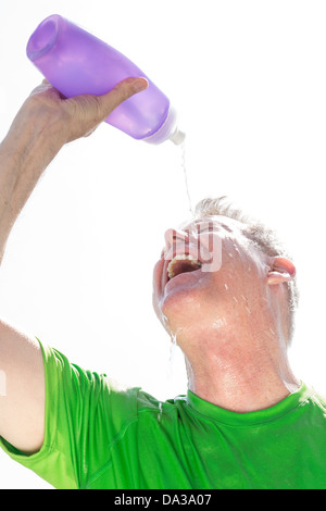 Homme senior versant de l'eau sur son visage pour soulager l'épuisement dû à la chaleur, États-Unis Banque D'Images