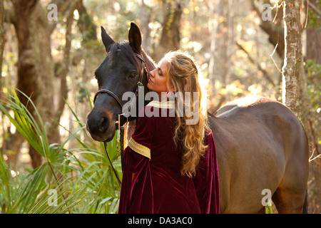 Femme en robe médiévale à cheval en forêt Banque D'Images