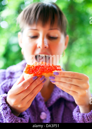 Femme mangeant le sandwich avec du caviar rouge Banque D'Images