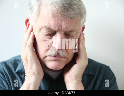 Homme plus âgé détient les deux mains à sa mâchoire supérieure près des oreilles Banque D'Images
