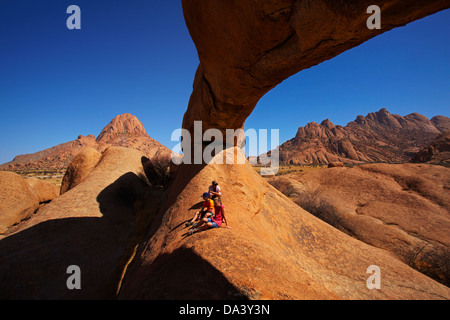 En vertu de la famille rocher naturel arche à Spitzkoppe (à gauche), et Pondok Montagnes en distance (à droite), la Namibie, l'Afrique Banque D'Images