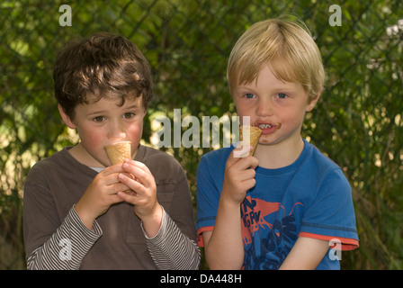 Deux garçons de 6 ans, manger des glaces à une fête d'été, feuille, Hampshire, Royaume-Uni. Banque D'Images